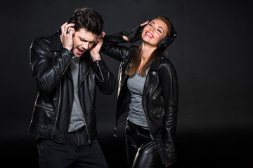 Fototapeta na wymiar beautiful couple in headphones and leather jackets listening music isolated on black