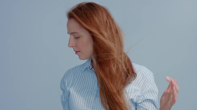 gingerhead red hair, ginger hair model with blue big eyes in studio with blowing hair in slow motion from 60fps. Beauty straight shiny hair blowing,