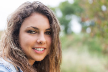Fototapeta premium Portrait of smiling tanned longhair brunette teenage girl with white teeth outdoors closeup.