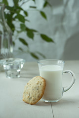 Oatmeal cookies with a glass of milk, light and white photography in a rustic style, village and countryside wooden theme