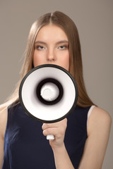 Woman holding a loud speaker. Portrait of a beautiful fashion woman. Gromophone foreground