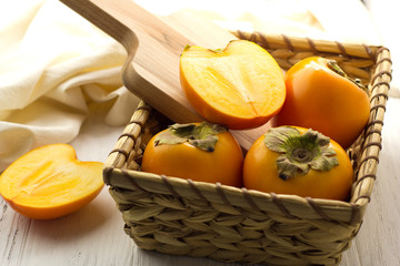 Fototapeta na wymiar persimmon in a basket on a light background