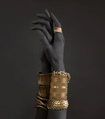 Black woman's hands with gold jewelry. Oriental Bracelets on a black painted hand.