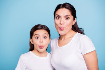 Close up photo beautiful two people brown haired mom little daughter friends look silly eyes opened tongue out of mouth straw shape figure playing wear white t-shirts isolated bright blue background