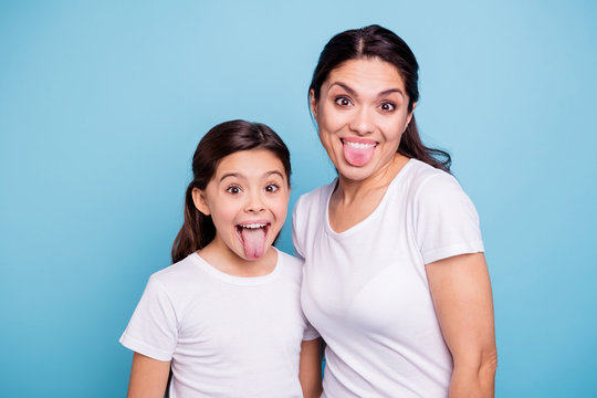 Close up photo beautiful two people brown haired mom little daughter friends hipsters silly mouth opened tongue out fooling around playing wear white t-shirts isolated bright blue background