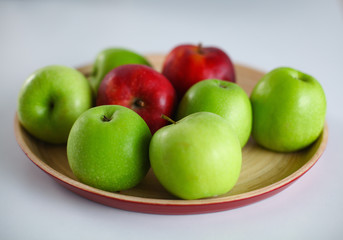 Green and red apple lies on a white table