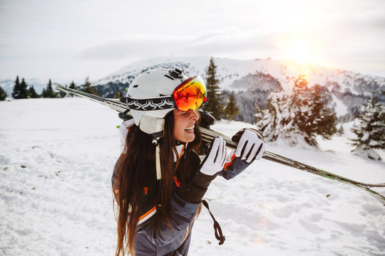 Portrait of beautiful woman with ski and ski suit in winter mountain