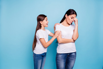 Close up photo two people brown haired mum small little daughter disinterested hands arms on shoulder ask speak tell talk mistakes sorry wear white t-shirts isolated bright blue background