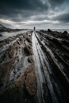 Anonymous person on rough stone shore