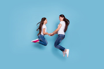 Fototapeta na wymiar Full length body size profile side view of two nice adorable lovely attractive cheerful funny slim sporty people in white t-shirt holding hands having fun isolated over blue pastel background