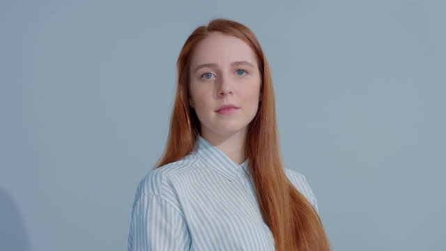 gingerhead red hair model turning to the camera on blue background. BEauty shiny stright red ginger hair