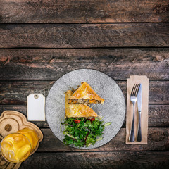 Strudel with stewed cabbage and meat, served on the ceramic plate with the cutlery and the glass of beverage.