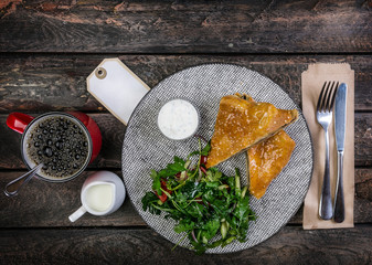 Strudel with mushrooms , cheese and vegetable salad, served on the ceramic plate with the cutlery and the cup of coffee.