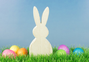 Easter bunny with colorful eggs , green meadow and blue sky, copy space
