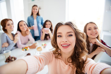 Close up portrait amazing beautiful she her diversity ladies sit round big white table in bright kitchen hold cups hot beverage glad make take selfies  girls day night holiday indoors