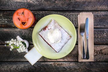 Strudel with cherry , served on the ceramic plate with the ice cream,cutlery and the glass of beverage, decorated with the flowers.