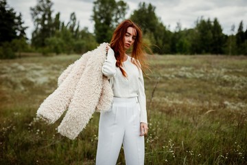 stylish young red haired woman posing outdoors 