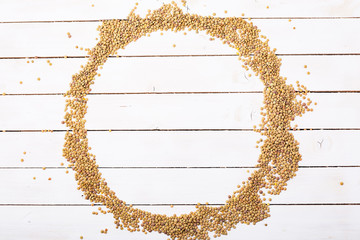 Raw dry green lentil seeds on white wood background.