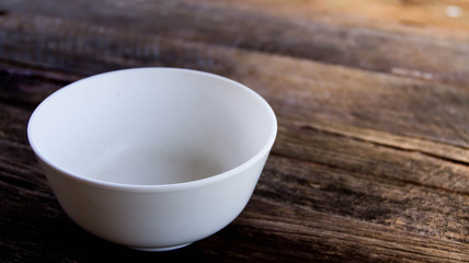White food bowl placed on a dark wood floor.