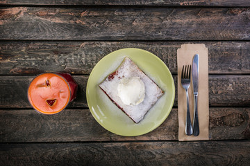 Strudel with cherry and vanilla ice cream, served on the ceramic plate with the cutlery and the glass of beverage.