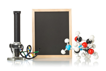 Blank, empty, black chalkboard with microscope, molecule model and DNA model over white