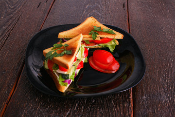 Vegetarian sandwich with tomato on a black plate