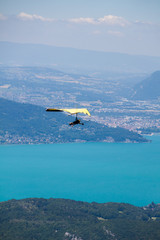 Hang-glider Instructor Flying in Hang-glider with Customer over Annecy Lake Through Mountain Landscape and Cities