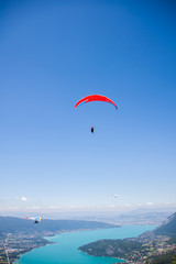 Hang-glider and Paraglider Flying over Annecy Lake Through Mountain Landscape and Cities