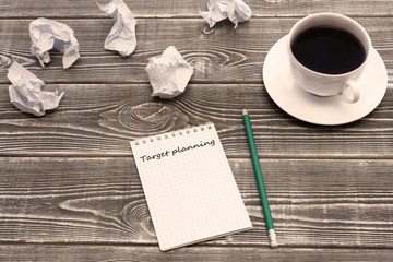 Planning goals on a Notepad sheet, a Cup of coffee, crumpled paper on a wooden table background. business ideas, planning.