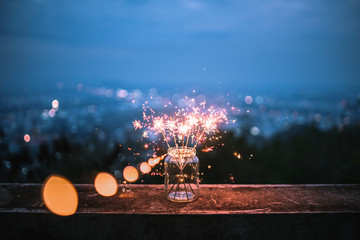 Sparklers in a glass jar that bokeh cities background. 
