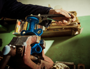 senior man holding metallic detail with rusty vintage vices 