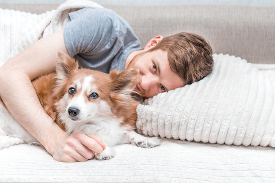 Young man lying in bed hugging a dog