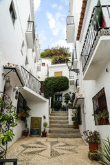 Fototapeta premium Small hilly alley with white fasedes and flowers at the balconies on a summer day