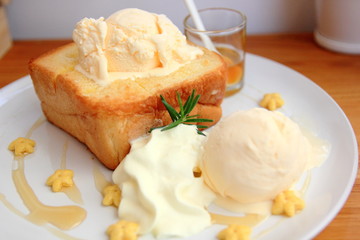 Honey Toast, a square toast baking and topped with vanilla ice cream and honey sauce served and whip cream. Top view. 