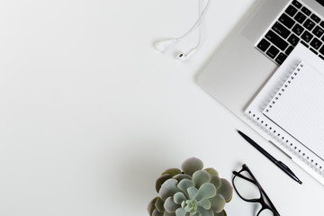 Top View of trendy White Office Desk with keyboard, white earphones and office supplies.