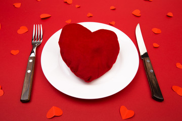 Heart on a plate for dinner. A romantic evening with hearts on red background.