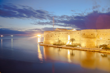 Naklejka premium A beautiful shot of the city of Taranto in south Italy by the main focus areas of the city at late sunset