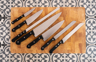 set of different kitchen knives on wooden board