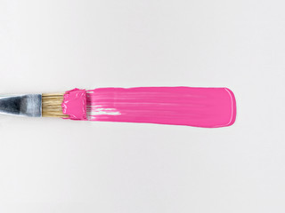 Paintbrush with smear of bright pink paint.