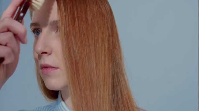 gingerhead red hair, ginger hair model comb her straight shiny hair closeup