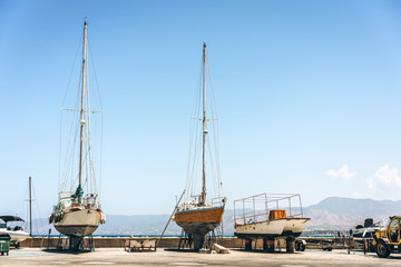 Obraz premium Old fishing boats standing on land near sea waiting for repair.