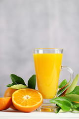Glass of orange juice with oranges fruit on wooden table.