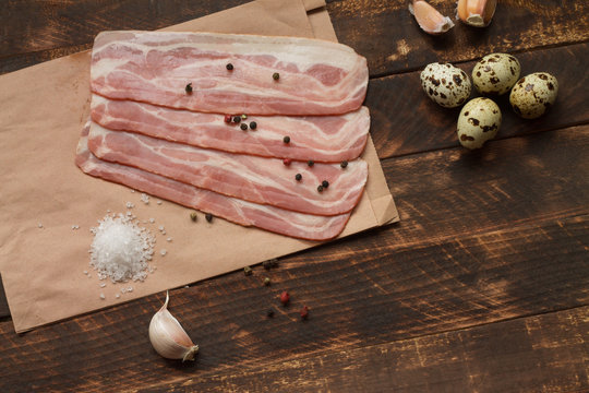 Raw bacon on a wooden plate