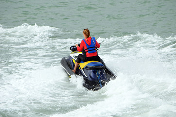 Young blonde woman speeding on a jet ski