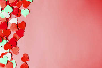 Pink paper background with red and green hearts with copy space. Valentine Day.