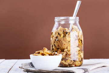 mushrooms in oil in a glass jar on white wooden background.