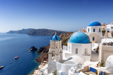 Fototapeta premium Niebieskie kopuły kościołów w Oia na skraju krateru wulkanu na Santorini, Cyklady, Grecja