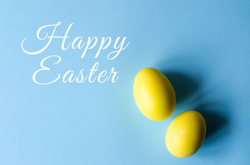 Two Easter eggs of yellow color on a blue background.