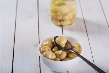 mushrooms in oil in ceramic bowl on white wooden background.