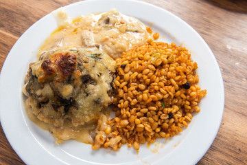 Kofte meatball covered with mushroom and bechamel sauce and bulgur pilav
